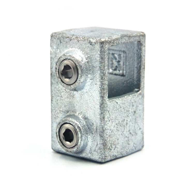 Racor en T metálico corto plateado para tubos cuadrados de 25 mm. Dos tornillos sin cabeza con hexágono en los laterales y abertura cuadrada superior para unión vertical de dos tubos. Superficie ligeramente texturizada, resistente.