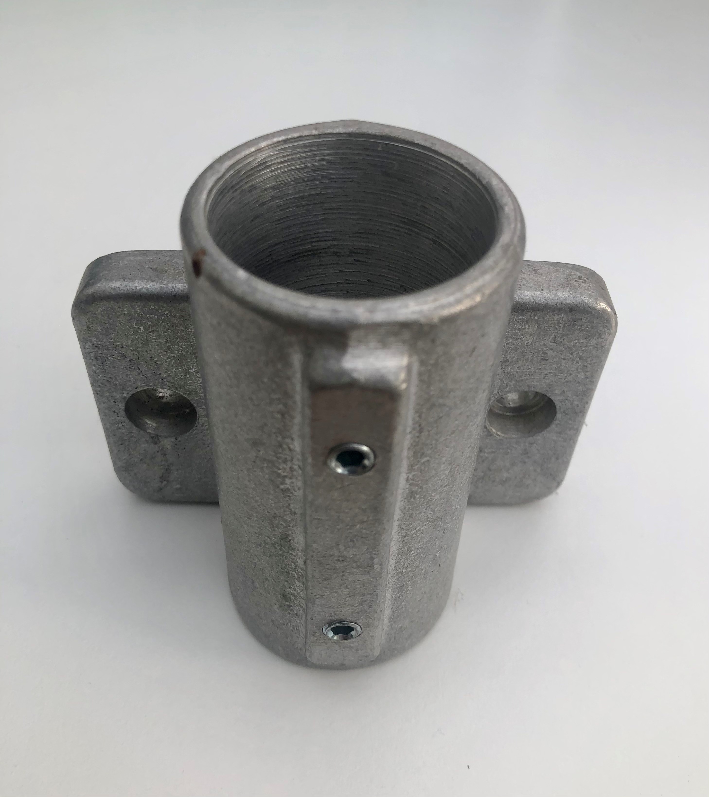 Wandlager aus rohem Aluminium, matte unpolierte Oberfläche. Zylindrische Öffnung mit sichtbaren Innenrillen an der Oberkante für 40mm Rohr. Seitlich zwei Madenschrauben zur Rohrbefestigung. Zwei Flansche mit Bohrung zur Wandmontage.